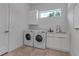 Bright laundry room with modern washer and dryer, white cabinetry, countertop space, and a window for natural light at 2124 Clematis Pl, Sarasota, FL 34239