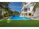 Expansive backyard showcasing a stunning pool, manicured lawn, and a luxurious three-story home at 227 S Harbor Dr, Holmes Beach, FL 34217