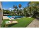 Lush backyard with a pool, hot tub, manicured lawn, and a fun cornhole game setup at 227 S Harbor Dr, Holmes Beach, FL 34217
