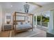 Serene bedroom with a stylish four-poster bed, coastal decor, and a private balcony access at 227 S Harbor Dr, Holmes Beach, FL 34217