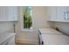 Bright laundry room with washer, dryer, built-in cabinets, and a window with a palm tree view at 227 S Harbor Dr, Holmes Beach, FL 34217