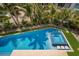Aerial view of a large backyard pool and hot tub surrounded by palm trees and well-maintained landscaping at 227 S Harbor Dr, Holmes Beach, FL 34217