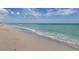 A tranquil beach scene features soft sand meeting the turquoise water under a clear sky at 234 Padova Way, North Venice, FL 34275