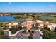 An aerial view features the clubhouse with a terracotta roof, surrounded by golf course, and a lake at 234 Padova Way, North Venice, FL 34275