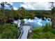 A wooden dock with benches sits on a lake, surrounded by lush greenery and reflecting the sky at 234 Padova Way, North Venice, FL 34275