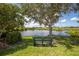 Scenic view of a tranquil pond with a bench under a large tree, perfect for relaxation and enjoying the outdoors at 234 Padova Way, North Venice, FL 34275