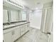 Bathroom with dual sinks, granite countertops, tiled floors, and a glass-enclosed shower at 2425 Maclachlan St, Port Charlotte, FL 33953