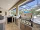 Outdoor kitchen with stone counter, stainless steel appliances, and screened-in pool view perfect for entertaining at 336 165Th Ne Ct, Bradenton, FL 34212
