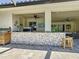 Covered outdoor kitchen area with a grill, bar, seating, and stylish stone detailing at 336 165Th Ne Ct, Bradenton, FL 34212