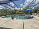 A beautiful screened-in pool and spa area with a blue umbrella, lounge chairs, and lush landscaping at 336 165Th Ne Ct, Bradenton, FL 34212