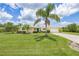 Well-maintained front yard with lush green grass and mature palm trees, showcasing the home's inviting facade and blue door at 336 Highland Shores Dr, Ellenton, FL 34222