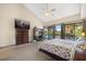 Carpeted bedroom with vaulted ceiling and fan overlooks a pool, workspace, and built-in dresser with TV at 3658 Torrey Pines Way, Sarasota, FL 34238