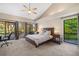 Spacious carpeted bedroom with vaulted ceiling and fan provides access to a balcony with views of the manicured landscape at 3658 Torrey Pines Way, Sarasota, FL 34238