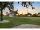 Scenic golf course view featuring lush greenery, mature trees, a sand trap, and sunrise sky at 3658 Torrey Pines Way, Sarasota, FL 34238