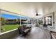 Covered porch overlooking the lawn and waterway features tile flooring and comfortable seating with a ceiling fan at 3715 Bamboo Ter, Bradenton, FL 34210