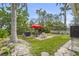 Large backyard with patio, dining table with umbrella, grill and tropical landscaping, ideal for outdoor activities at 403 29Th Nw St, Bradenton, FL 34205