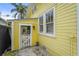 Exterior view of yellow home featuring small garden and window with shuttered blinds at 403 29Th Nw St, Bradenton, FL 34205
