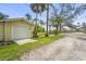 Exterior view of detached garage with white door and yellow siding, surrounded by lush landscaping and blue skies at 403 29Th Nw St, Bradenton, FL 34205