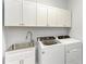 Laundry room featuring washer, dryer, stainless steel sink, and white cabinets at 4324 Dairy Ct, Lakewood Ranch, FL 34211