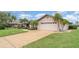 Inviting single-Gathering home featuring a spacious two-car garage, a well-manicured lawn, and mature palm trees at 4330 Presidential Avenue E Cir, Bradenton, FL 34203