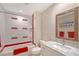 Updated bathroom with a shower over tub, marble countertop vanity, framed mirror and white and red accents at 444 S Polk Dr, Sarasota, FL 34236