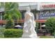 Detailed statue of Neptune in front of a restaurant with outdoor seating and palm trees at 444 S Polk Dr, Sarasota, FL 34236