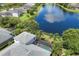 Aerial view of a home with a screened-in pool area overlooking a serene lake and lush landscaping at 4714 Seneca Park Trl, Bradenton, FL 34211