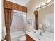 Clean bathroom with a shower-tub combo, wood vanity, neutral tile, and decorative accents providing a comfortable space at 5179 Cantabria Crst, Sarasota, FL 34238