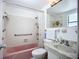 Cozy bathroom features a pink bathtub, white tile, and marble-topped sink at 5572 Shadow Lawn Dr, Sarasota, FL 34242