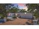 Charming single-story home featuring a white exterior, pink shutters, mature landscaping, and a spacious driveway at 5572 Shadow Lawn Dr, Sarasota, FL 34242