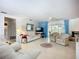 Bright living room featuring white furniture, light flooring, and large windows with blue curtains at 5572 Shadow Lawn Dr, Sarasota, FL 34242