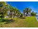 Backyard featuring mature palm trees, green lawn, and serene waterfront views from the rear of the house at 564 Spanish N Dr, Longboat Key, FL 34228