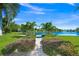 Beautiful backyard with a brick path leading to a serene lake view, surrounded by lush greenery and palm trees at 564 Spanish N Dr, Longboat Key, FL 34228