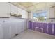 Empty kitchen featuring white cabinets, window, tile flooring, and plaster walls awaiting renovation at 564 Spanish N Dr, Longboat Key, FL 34228