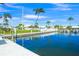 Scenic waterfront view showcasing a well-maintained property with a white fence, boat docks, and tropical palm trees at 564 Spanish N Dr, Longboat Key, FL 34228