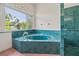 A bathroom soaking tub with green marble surround, arched window, and separate glass block shower at 6103 6Th Nw Ave, Bradenton, FL 34209