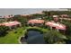 Aerial view of a condo complex overlooking a pond and ocean, with well-maintained landscaping and red tile roofs at 6472 Seagull Dr # 301, Bradenton, FL 34210