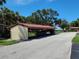 View of a multi-car carport with a tile roof, providing covered parking for residents in this tropical community at 6472 Seagull Dr # 301, Bradenton, FL 34210