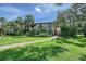 Exterior view of condo building with tropical landscaping, a sidewalk, and a second-story balcony at 6472 Seagull Dr # 301, Bradenton, FL 34210