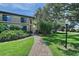 Exterior shot of a two-story condo building with a brick walkway, lush greenery, and mature trees at 6472 Seagull Dr # 301, Bradenton, FL 34210