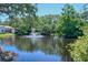 Scenic pond view with a central fountain, surrounded by lush greenery, reflecting the blue sky at 6472 Seagull Dr # 301, Bradenton, FL 34210