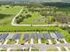 A row of charming single-Gathering homes, each with well-manicured lawns, set against a vast green field and pond backdrop at 6528 166Th E Pl, Parrish, FL 34219