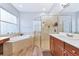 Bright primary bathroom with a standalone tub, a glass shower, tile floors, and and sink vanities at 6845 74Th Street E Cir, Bradenton, FL 34203