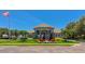 Clubhouse exterior featuring a well-maintained lawn, colorful flowers, and palm trees, exuding a welcoming community at 6845 74Th Street E Cir, Bradenton, FL 34203