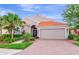 Charming single-story home featuring a red tile roof, brick driveway, and lush tropical landscaping at 6845 74Th Street E Cir, Bradenton, FL 34203