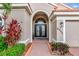 Close-up of an entryway showcasing double doors with decorative glass and surrounding tropical landscaping at 6845 74Th Street E Cir, Bradenton, FL 34203