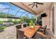Enclosed patio featuring a dining table, seating area, fire pit, television, and lush greenery, perfect for entertaining at 6845 74Th Street E Cir, Bradenton, FL 34203