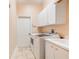 Bright laundry room featuring a washer, dryer, utility sink, and storage cabinets at 7521 Aralia Way, Seminole, FL 33777
