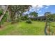 An expansive backyard features lush green grass, a colorful garden, and a screened lanai, ideal for relaxing and entertaining outdoors at 7604 Weeping Willow Cir, Sarasota, FL 34241