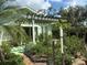 The lush backyard features a green lawn, garden, and pergola providing shade and visual appeal at 7604 Weeping Willow Cir, Sarasota, FL 34241